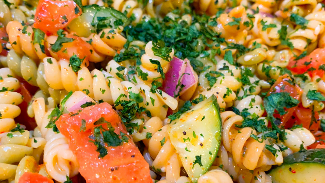 close up of colorful pasta salad with cucumbers and tomatoes