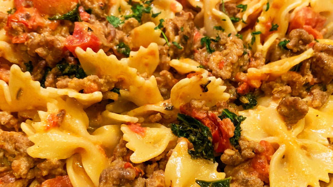 closeup photo of creamy kale and sausage pasta