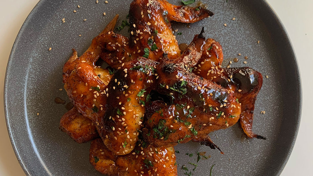 honey sriracha wings on a gray plate with sesame seeds
