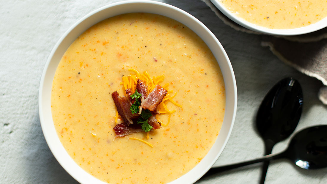 2 bowls of loaded baked potato soup with spoons